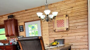 A wooden-paneled dining area with a chandelier, a chessboard, and a bowl of fruit on the table. - Secluded 5-Bedroom Lodge with Private Lake – Perfect for Large Groups! (Perryville)