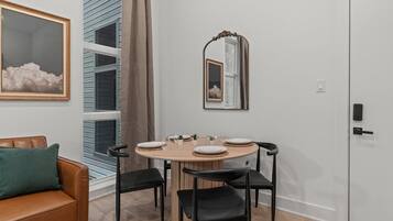 A dining area with a round wooden table, black chairs, and a mirror above it.