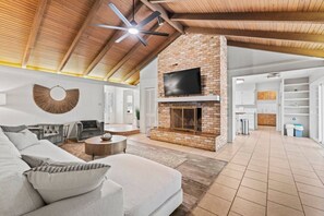 A spacious living area with a fireplace, a sofa, and a television mounted on a brick wall.