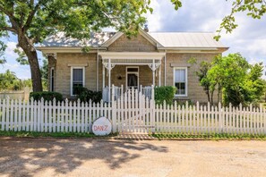 A two-story house with a front porch, a picket fence, and a driveway.