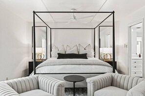 Uma cama com dossel de design moderno, um ventilador de teto e uma mesa de cabeceira com abajur.
