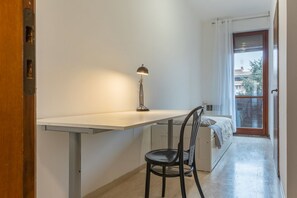 A small room with a desk, chair, and a bed.