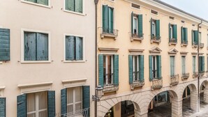 Eine Reihe von Gebäuden mit Rundbogenarkaden und grünen Fensterläden.