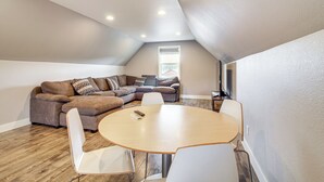 A loft-style living area with a round wooden table, white chairs, a brown sectional sofa, and a ceiling with recessed lighting. - 1 Mi to Oregon Dunes: Quiet Getaway w/ Deck (Lakeside)