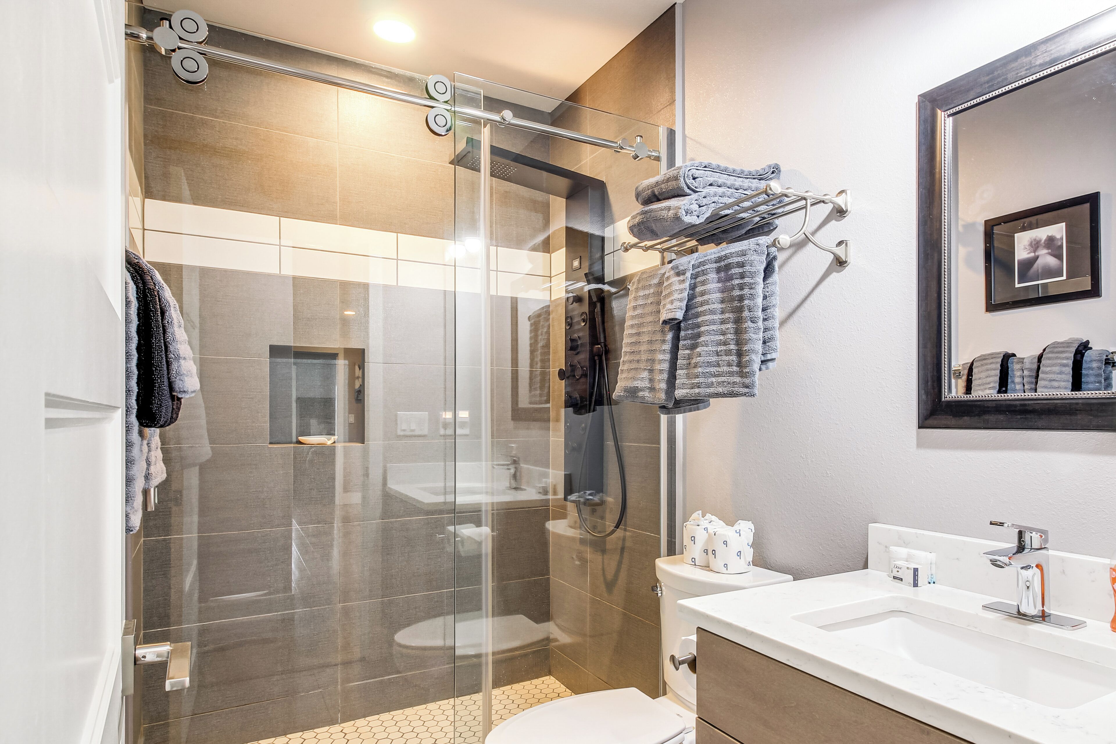 Un baño moderno con cabina de ducha de vidrio, un lavabo blanco y un espejo grande.