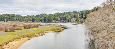 Un río con un puente, rodeado de árboles y una zona verde.