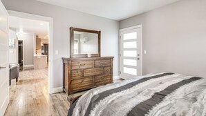 A bedroom with a wooden dresser, a large mirror, and a striped bedspread. - 1 Mi to Oregon Dunes: Quiet Getaway w/ Deck (Lakeside)
