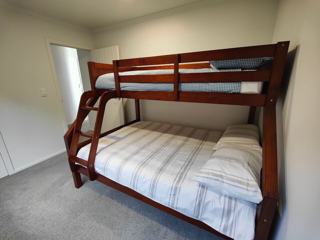 A bunk bed with a wooden frame and striped bedding.