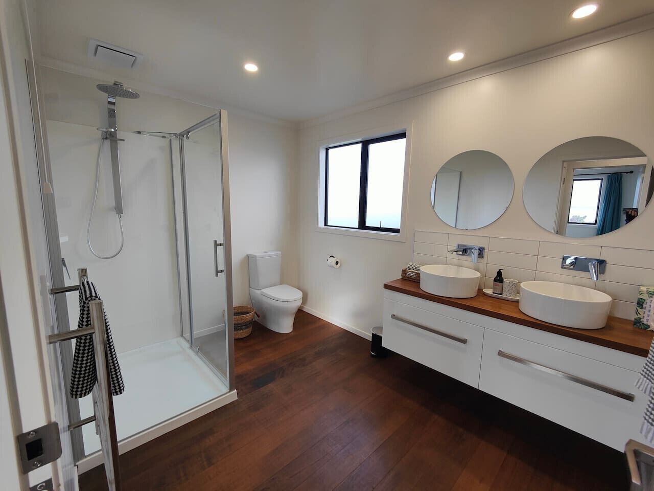 Une salle de bain moderne avec une douche à parois de verre, des toilettes et un meuble-lavabo doté de deux vasques.
