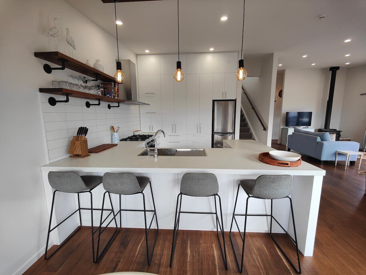 Une cuisine moderne dotée d’un îlot central, de tabourets de bar et de luminaires suspendus.