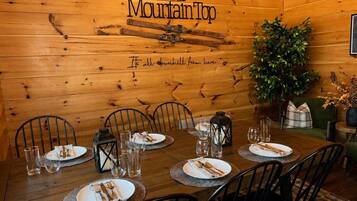 Ein Esszimmer aus Holz mit einem für sechs Personen gedeckten Tisch, Stühlen, einer Pflanze und einem Schild mit der Aufschrift 'The Mountain Top'.