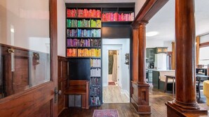 A hallway with a wooden floor, a bookshelf filled with books, and a rug.