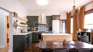 A modern kitchen with dark cabinets, a white refrigerator, and a wooden dining table.