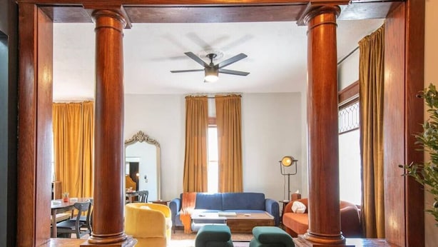 A spacious living room with a wooden floor, a blue sofa, and a ceiling fan.