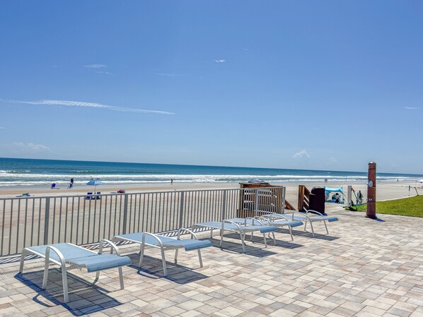 A beachside patio with metal benches and a view of the ocean.