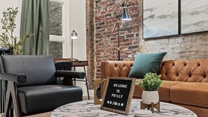 Un salon moderne avec un canapé en cuir, un fauteuil noir, une table basse ronde en marbre et une pancarte sur laquelle on peut lire « BIENVENUE À PHILADELPHIE ».