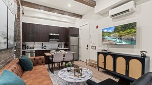 Un salon moderne avec un canapé en cuir marron, une table basse en marbre et un grand téléviseur à écran plat.