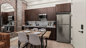 Une cuisine moderne avec des meubles en bois foncé, des appareils en acier inoxydable et un coin repas comprenant une table et des chaises en bois.