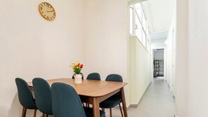 A dining area with a wooden table and six chairs, a vase with flowers, and a wall clock. - Amazing Apartment in Condesa (Ciudad de México)