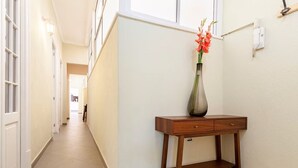 A hallway with a wooden console table, a vase with flowers, and a light switch on the wall. - Amazing Apartment in Condesa (Ciudad de México)