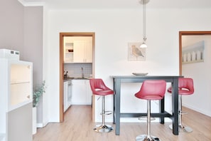 Una cucina moderna con mobili bianchi, un frigorifero in acciaio inossidabile e un tavolo da pranzo in legno con quattro sedie rosse.