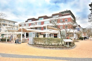 Un edificio residenziale a più piani con una zona esterna coperta, una targa e un piccolo giardino.