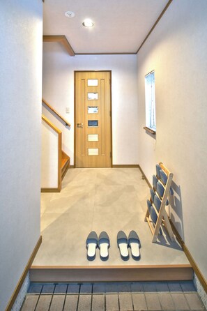 A hallway with a wooden door, a shoe rack, and a pair of shoes on the floor.