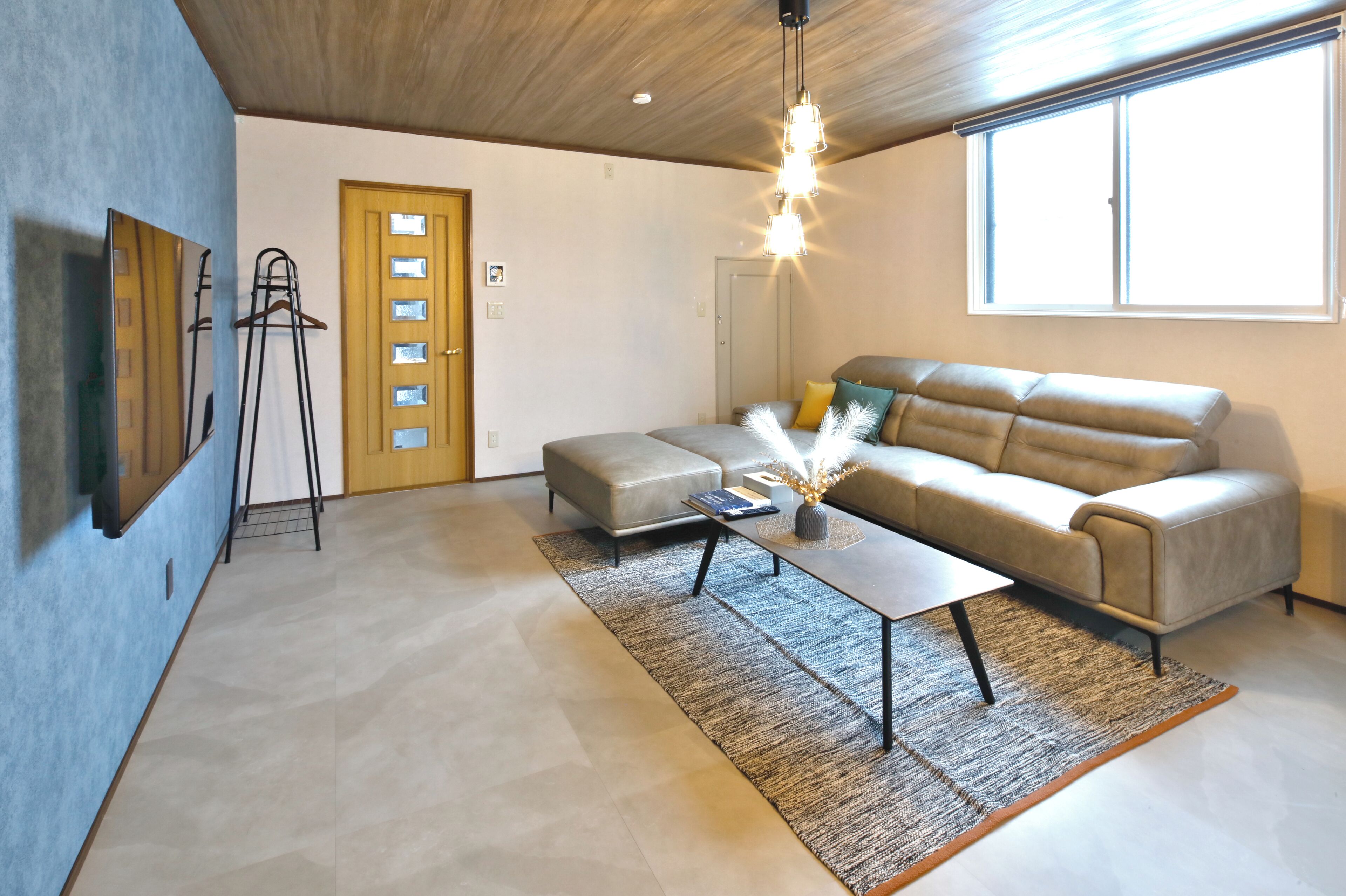 A modern living room with a sofa, a coffee table, and a hanging light fixture.