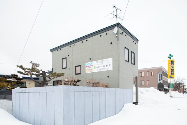 A building with a signboard, a satellite dish, and a snow-covered area in front. - GUESTHOUSE LE REPOS (Bihoro)