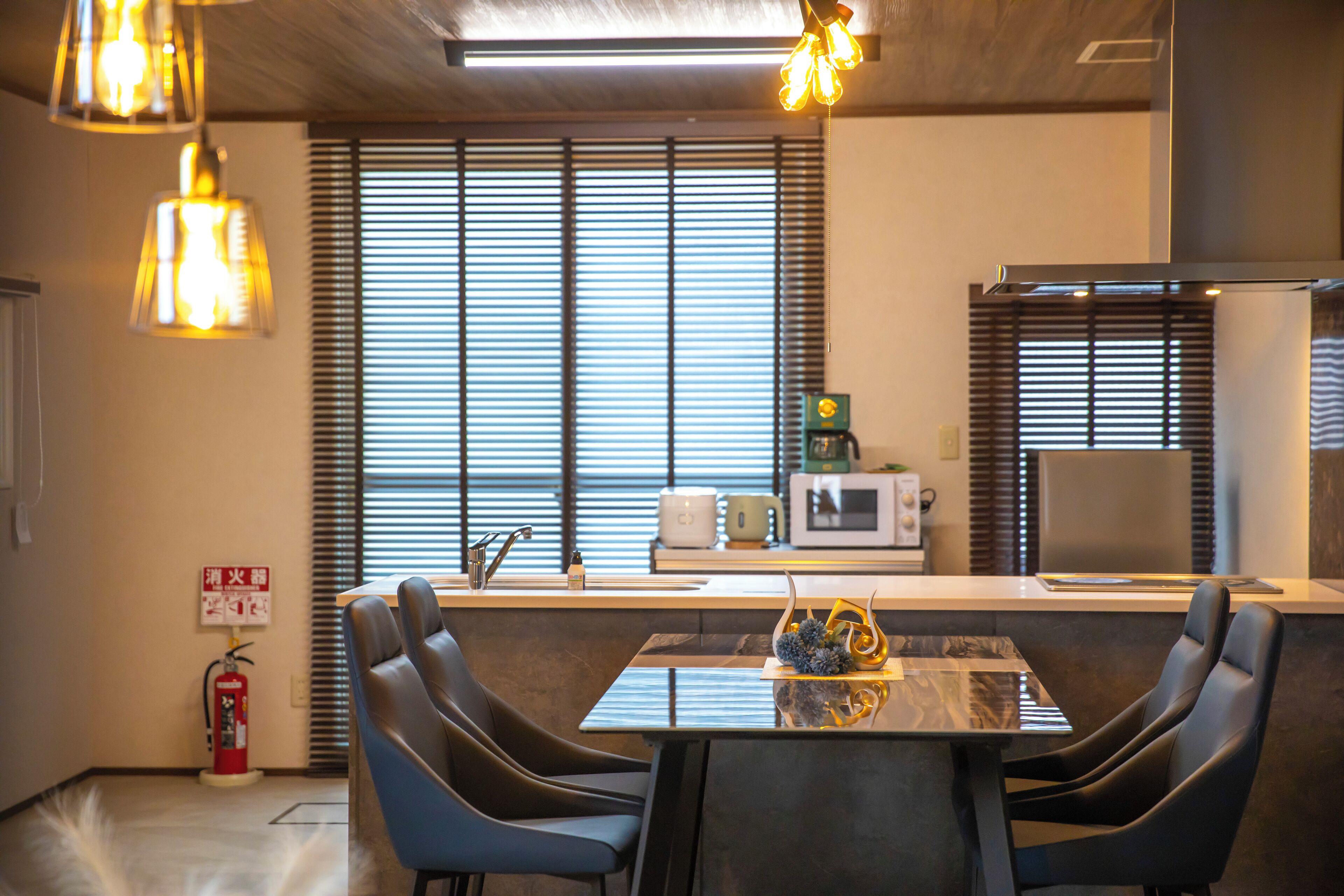 A modern kitchen with a central island, black chairs, and pendant lighting.
