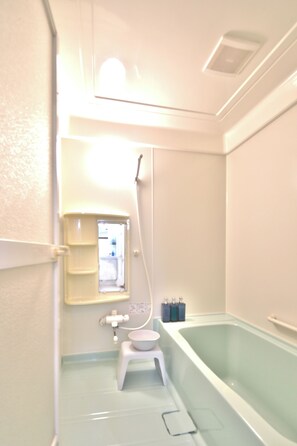 A bathroom with a bathtub, toilet, and a small window.