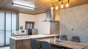 Una cucina moderna con isola centrale, elettrodomestici integrati e zona pranzo con un tavolo lungo e sedie.