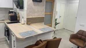 Una cocina moderna con cafetera integrada, encimera de madera y un reloj en la pared.