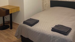 Un dormitorio con cama, escritorio y silla.