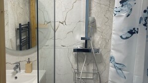 Un baño con ducha, lavamanos y espejo.