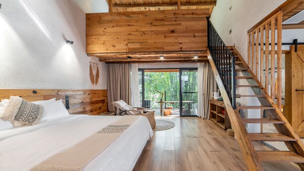 A spacious bedroom with a large bed, wooden ceiling, and a staircase leading to an outdoor area. - Yingde YeDuGu Resort (Qingyuan)
