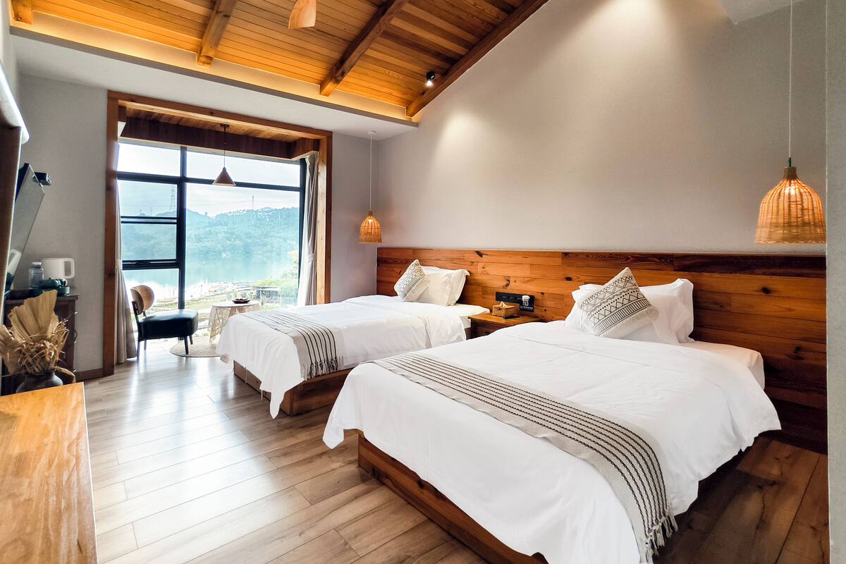 Ein Schlafzimmer mit zwei Betten, Holzboden, Deckenventilator und Blick ins Freie.