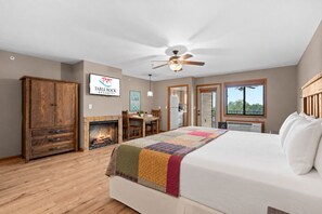 Un dormitorio con cama, armario de madera, chimenea, zona de comedor y vistas al exterior.