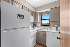 A kitchen with a refrigerator, stove, sink, and window.