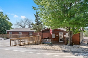 A rustic wooden building with a porch, a flag, and a bench. - King Suite with Lake View | Walk to Table Rock Lake | Less Than 5 Min to Silver Dollar City (Branson)