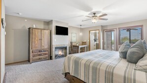 A bedroom with a bed, a wooden wardrobe, a fireplace, a ceiling fan, and a TV mounted on the wall. - King BDRM Lake Condo-Lake View, Resort Amenities, Discounts on Tickets & Golf! (Branson)