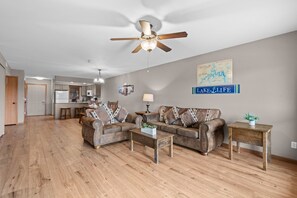A spacious living room with a ceiling fan, a dining area with a table and chairs, and a kitchen in the background. - Lake View Condo Near Silver Dollar City | Walk to Table Rock Lake | 2 Pools | Near 2 Marinas (Branson)