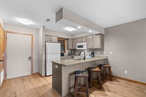 A modern kitchen with a central island, built-in appliances, and bar stools. - Lake View Condo Near Silver Dollar City | Walk to Table Rock Lake | 2 Pools | Near 2 Marinas (Branson)