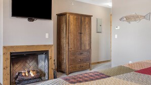 Una habitación con chimenea, un armario de madera, un televisor montado en la pared y un mural con motivos marinos.