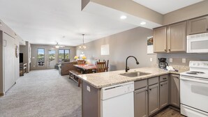 A kitchen with a dishwasher, stove, and microwave. There is a dining area with a table and chairs. - Resort  Perks, Golf/Ticket Deals- Lake View - Private  Deck! (Branson)