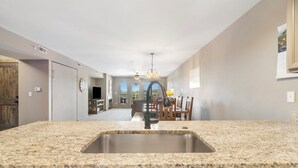 A kitchen with granite countertops, a stainless steel sink, and a dining area in the background. - Resort  Perks, Golf/Ticket Deals- Lake View - Private  Deck! (Branson)