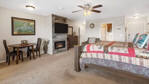 A bedroom with a bed, a fireplace, a television, and a dining area with a table and chairs. - Beautiful Lake View 1 BD with Jacuzzi Tub and Free Resort Amenities, Ticket Discounts! (Branson)