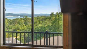 A room with a large window overlooking a forested area and a body of water.