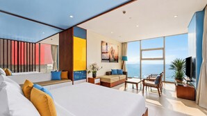 Ett modernt hotellrum med en stor säng, en sittgrupp och en balkong med utsikt över havet.
