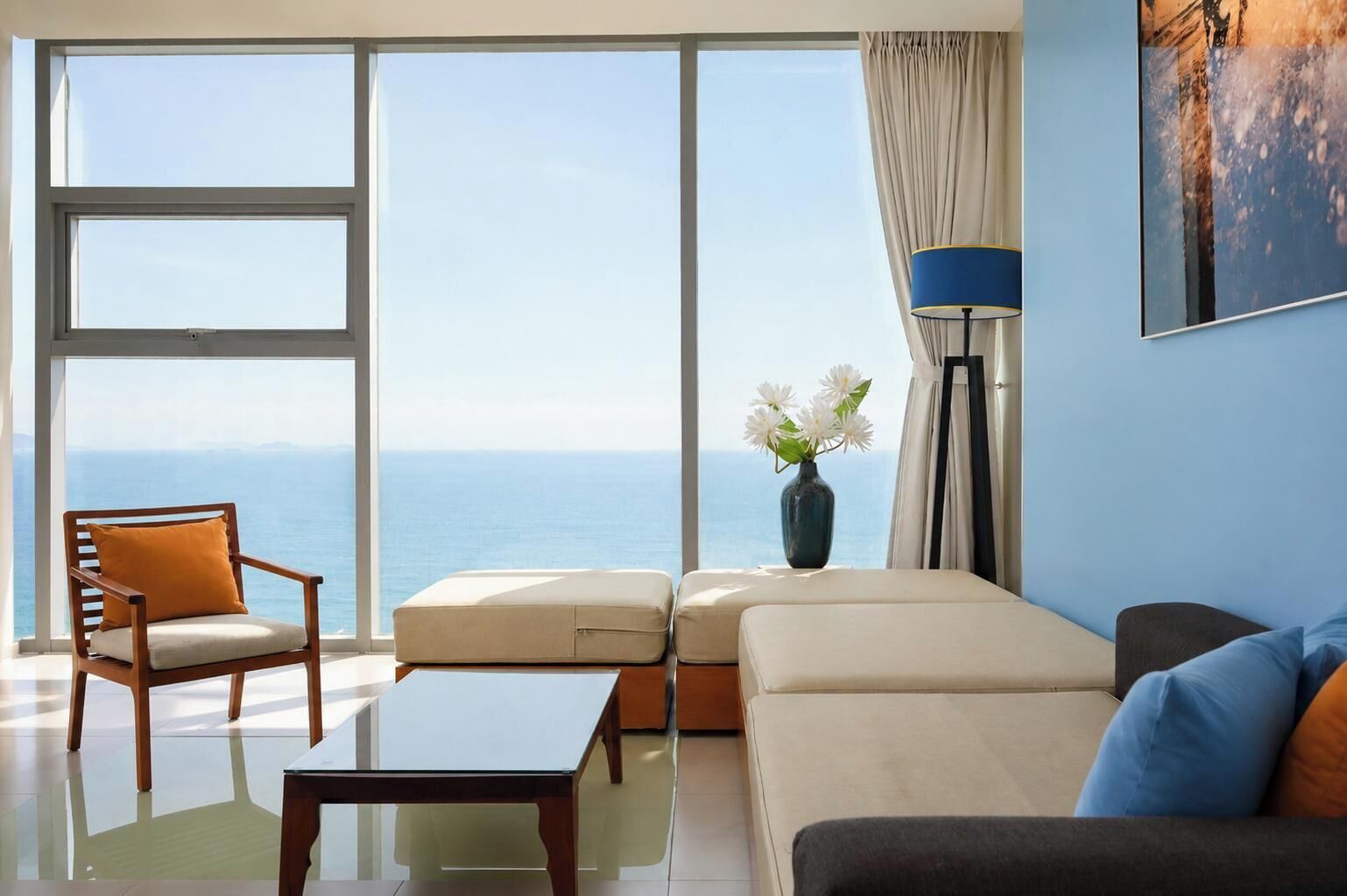 A modern living room with a view of the sea, a sofa, a chair, a coffee table, and a floor lamp.
